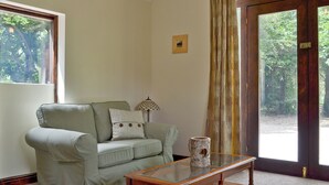 Een woonkamer met een lichtgroene bank, een bijzettafeltje en een groot raam met gordijnen.