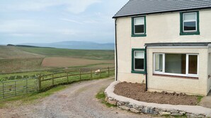 Ein zweistöckiges Haus mit Kiesweg und Steinbord.