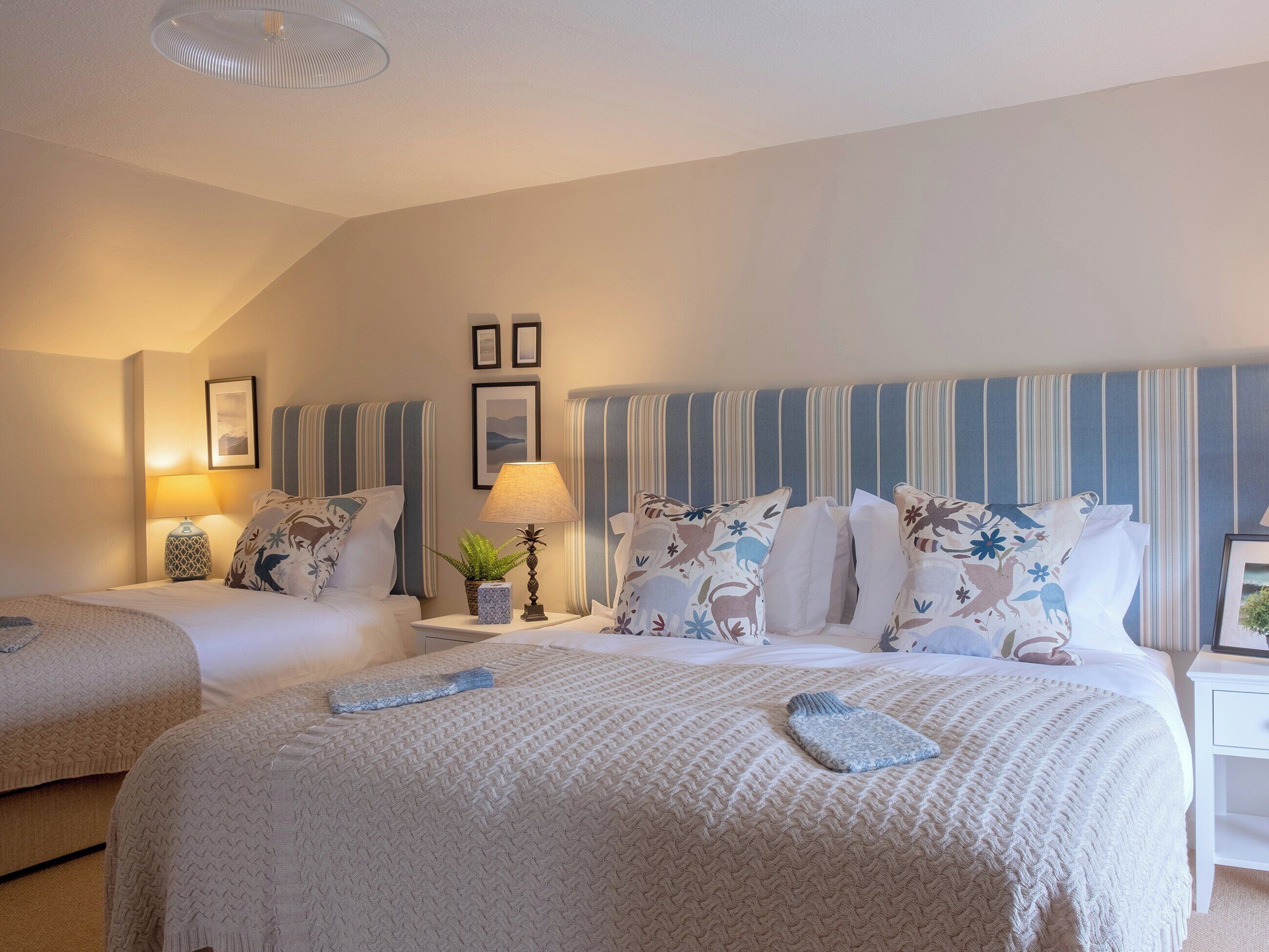 A hotel room with two beds, striped headboards, and a large window.