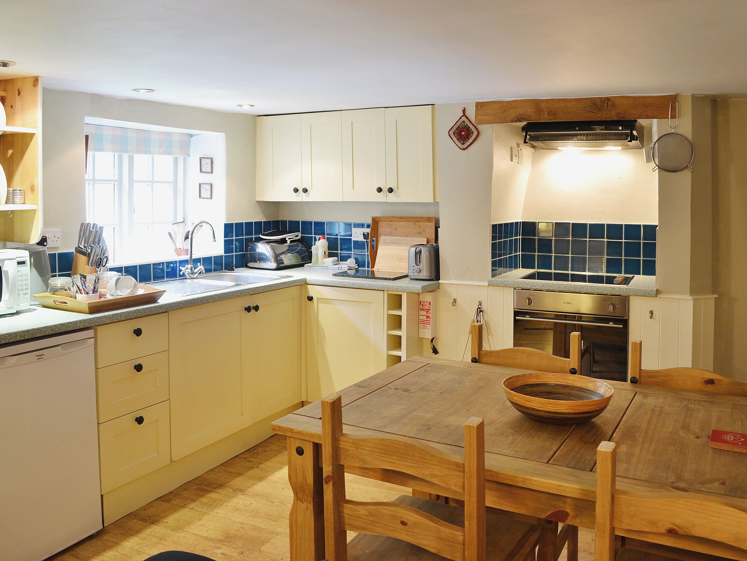 A kitchen with a wooden table, a toaster, a sink, and cabinets.