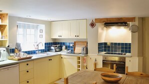 A kitchen with a wooden table, a toaster, a sink, and cabinets.