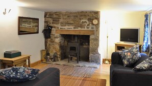A living room with a stone fireplace, a television, and two sofas with floral cushions.