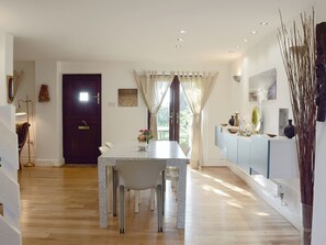 A dining area with a table, chairs, and a view through a window. - 2 bedroom accommodation in near Kilgetty (near Kilgetty)