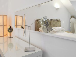 A modern bedroom with a large mirror, a bedside table, and a bed with a patterned headboard. - 2 bedroom accommodation in near Kilgetty (near Kilgetty)