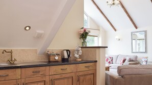 A kitchen with wooden cabinets, a coffee maker, and a kettle on the counter. - 3 bedroom accommodation in Llangennith, near Swansea (Llangennith, near Swansea)