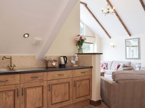 A kitchen with wooden cabinets, a coffee maker, and a kettle on the counter. - 3 bedroom accommodation in Llangennith, near Swansea (Llangennith, near Swansea)