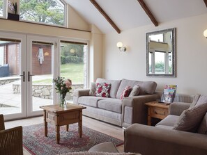 A living room with a sofa, a coffee table, and a mirror on the wall. - 3 bedroom accommodation in Llangennith, near Swansea (Llangennith, near Swansea)