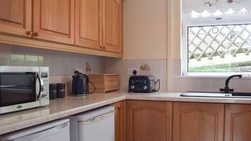 A kitchen with wooden cabinets, a microwave, a toaster, a kettle, and a dishwasher.