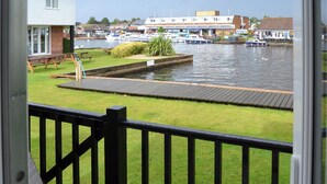 A view from a balcony overlooking a marina with boats, a grassy area, and a wooden dock.