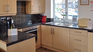 A modern kitchen with wooden cabinets, a black countertop, and a window with a view of the neighborhood.
