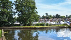 A calm water body with a wooden walkway and a row of houses in the background.