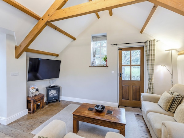 Un salon chaleureux avec un plafond en bois, un téléviseur à écran plat, une cheminée, une table basse en bois et un canapé beige.
