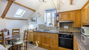 A kitchen with wooden cabinets, a dishwasher, a microwave, and a window with a view.