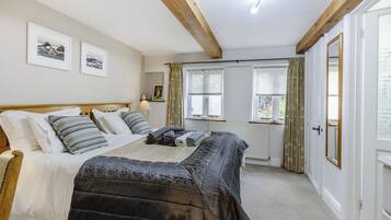 A bedroom with a bed, a window, a radiator, and a door.