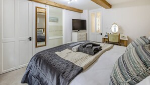 Una camera da letto con un letto, una televisione, una cassettiera, uno specchio e una porta che dà su un bagno.