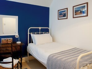 A bedroom with a bed, a desk, a chair, a lamp, and two framed pictures on the wall. - 3 bedroom accommodation in Middleton, Freshwater (Middleton, Freshwater)