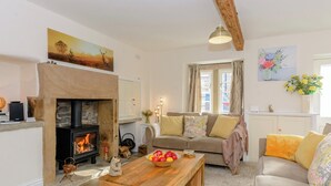 A cozy living room with a fireplace, a sofa, a wooden coffee table, and a painting on the wall. - 3 bedroom accommodation in Ashford-in-the-Water, near Bakewell (Ashford-in-the-Water, near Bakewell)