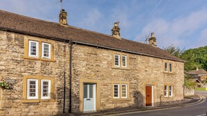A stone building with multiple windows and doors, a clear sky, and a road in front. - 3 bedroom accommodation in Ashford-in-the-Water, near Bakewell (Ashford-in-the-Water, near Bakewell)