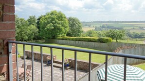 A balcony with a view of a green landscape, a brick wall, and a wooden fence. - 3 bedroom accommodation in Alwington, near Bideford (Alwington, near Bideford)
