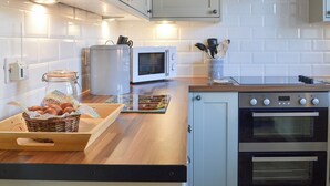 A modern kitchen with white cabinets, a microwave, an oven, and a wooden countertop. - 2 bedroom accommodation in Urray, near Dingwall (Urray, near Dingwall)