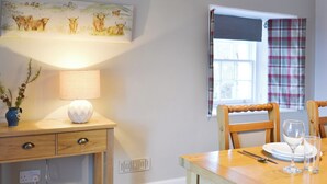 A dining area with a wooden table, chairs, a lamp, and a painting on the wall. - 2 bedroom accommodation in Urray, near Dingwall (Urray, near Dingwall)