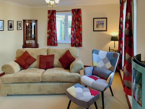 A living room with a sofa, armchair, and curtains.