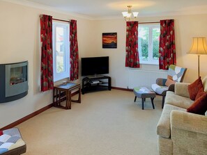 A living room with a flat-screen TV, a fireplace, a sofa, and a lamp.