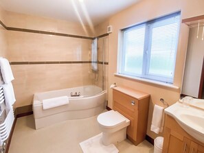 A bathroom with a bathtub, toilet, vanity, and a window. - 3 bedroom accommodation in Bamburgh (Bamburgh)