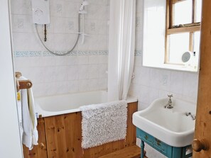 A bathroom with a wooden bathtub, a white sink, and a shower.