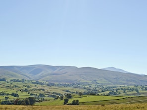 A panoramic view of rolling hills and a distant mountain range under a clear sky.