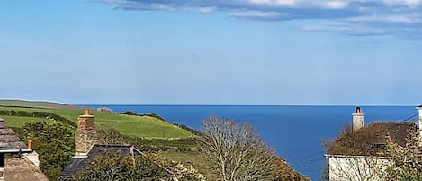 A coastal view with stone buildings, a clear sky, and the sea in the distance.