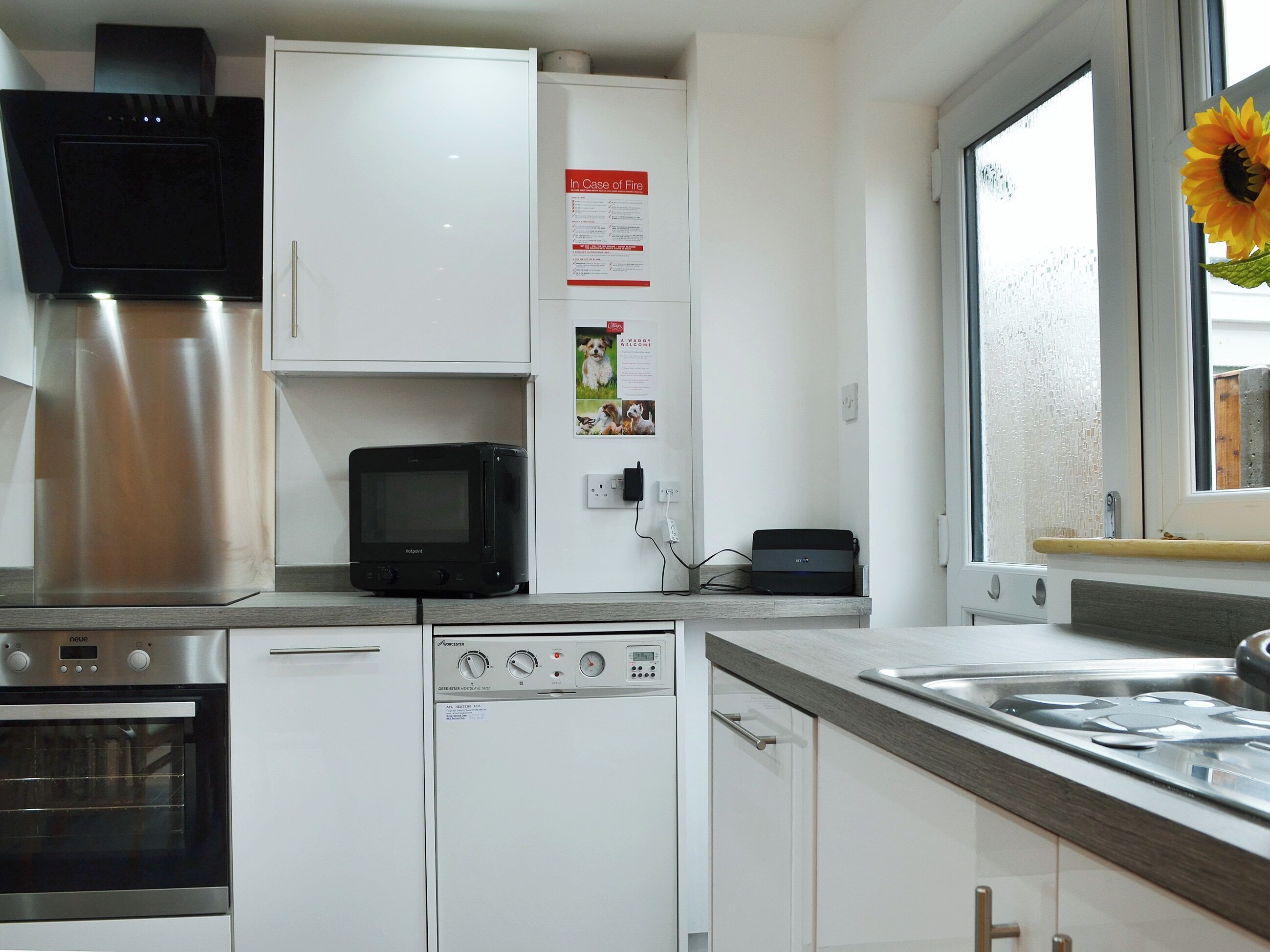 Une cuisine moderne équipée d’un four, d’un micro-ondes et d’un lave-vaisselle intégrés. Une fenêtre offre une vue sur l’extérieur.