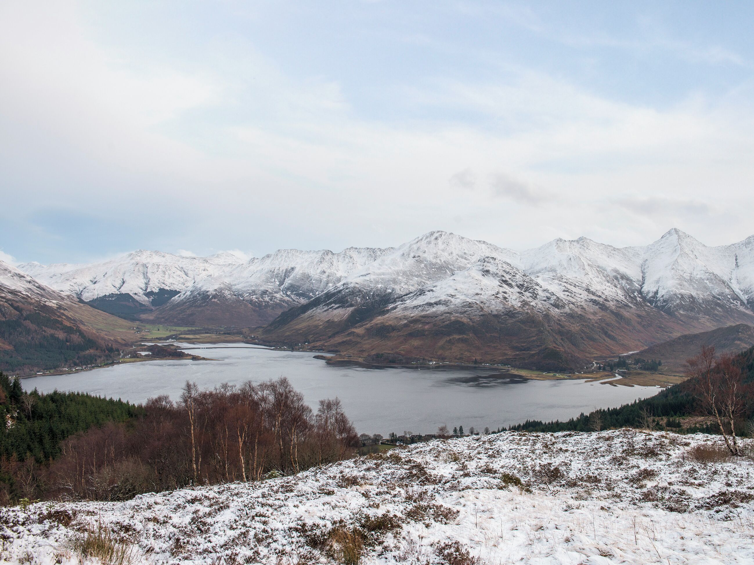 A mountainous landscape with a lake and snow-covered peaks.
