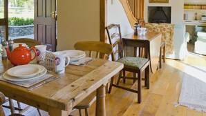 Un espace repas comprenant une table en bois, des chaises et un escalier.
