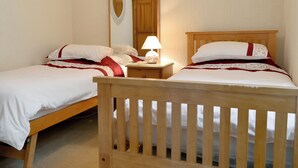 A double bed with a wooden headboard, a nightstand with a lamp, and a mirror on the wall. - 2 bedroom accommodation in Keswick (Keswick)