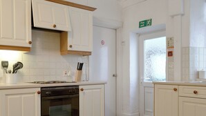 A kitchen with white cabinets, a stove, and a window with frosted glass. - 2 bedroom accommodation in Keswick (Keswick)