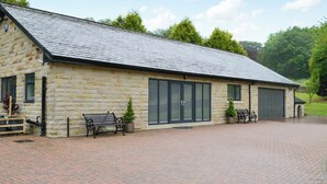 A stone building with a sloped roof, large windows, and a paved driveway.
