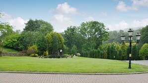 A paved area with a fountain, trees, and a lamp post.