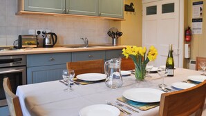 A dining area with a table set for four, a coffee maker, and a bottle of wine on the counter.