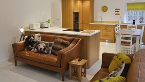 Una cocina moderna con armarios de madera, una isla central y un comedor con sillas blancas.