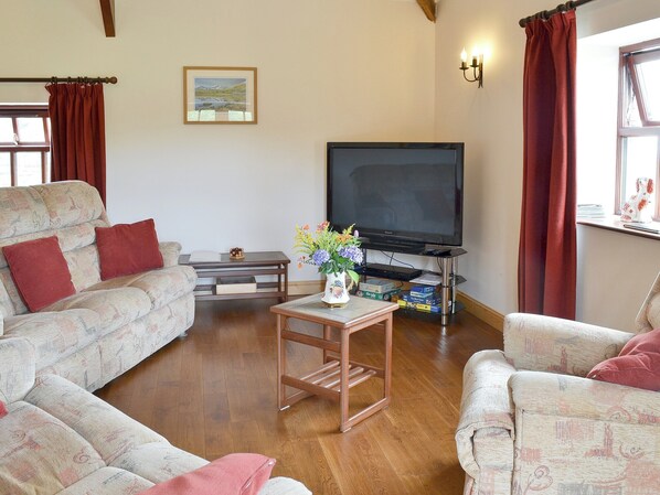 A living room with a sofa, armchairs, a coffee table, a TV, and a painting on the wall. - 3 bedroom accommodation in Bontnewydd, near Caernarfon (Bontnewydd, near Caernarfon)