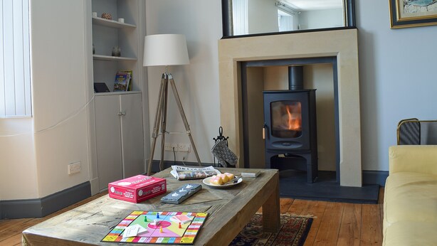 A living room with a fireplace, a table with board games, and a bookshelf.