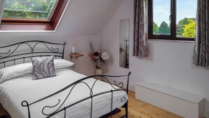 A bedroom with a skylight, a bed with white bedding, a bedside table with a vase, and a window with curtains. - 1 bedroom accommodation in Upton (Upton)