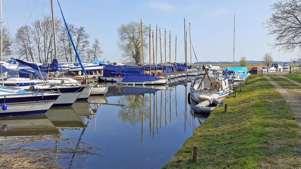 A marina with boats docked along a calm waterway, surrounded by grassy banks and trees. - 1 bedroom accommodation in Upton (Upton)