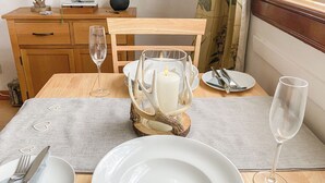 Una mesa de comedor dispuesta con platos blancos, cubiertos y un candelabro.