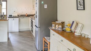 A kitchen with a refrigerator, dishwasher, and wooden countertop.
