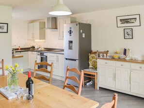 A modern kitchen with white cabinets, a stainless steel refrigerator, and a dining table with chairs.