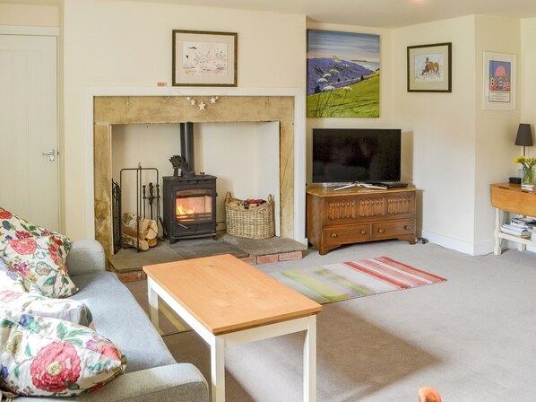 A living room with a fireplace, sofa, television, and artwork on the walls.