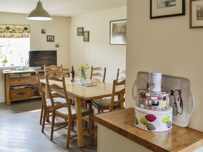 A dining area with a wooden table and chairs, a television, and framed pictures on the wall.