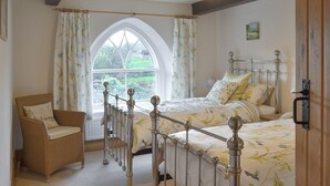 Una camera da letto con una grande finestra, un letto con testiera in metallo, una sedia e un lampadario.